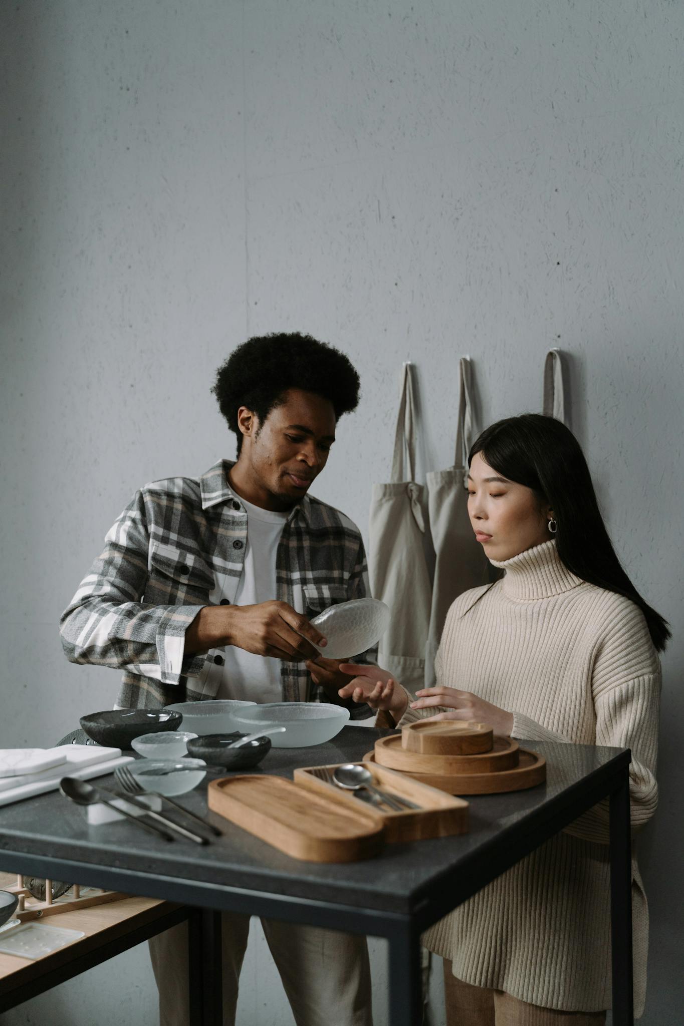 African American man and Asian woman examining dishware options in a modern setting.