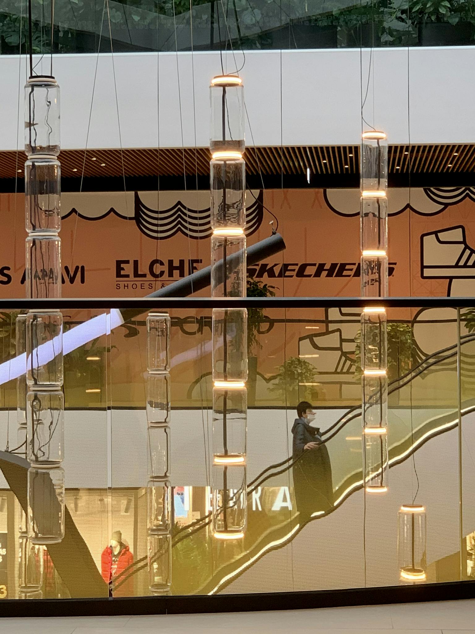 Intricate view of an escalator in a lively shopping mall with vibrant lighting.