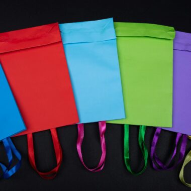 Vibrant flat lay of colorful shopping bags displayed on a black background, ideal for retail themes.
