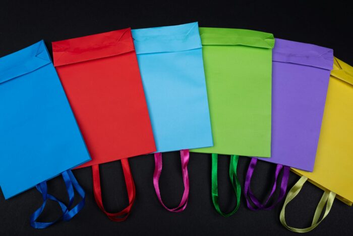 Vibrant flat lay of colorful shopping bags displayed on a black background, ideal for retail themes.